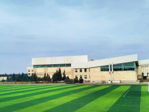 a large building with a large grass field in front at Arena Hotel Shirvan in Əli Bayramlı Stansiyası