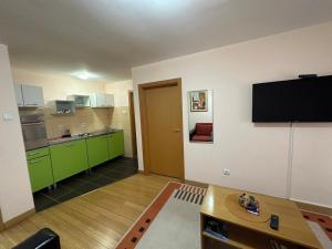 a kitchen with green cabinets and a flat screen tv at Apartmani Ušće in Trstenik