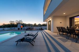 a house with a swimming pool and some chairs at Villa Roma Murvica ZadarVillas in Murvica