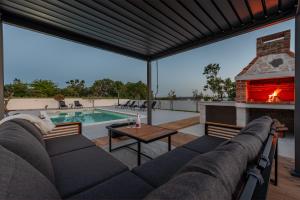 a patio with a couch and a fireplace next to a pool at Villa Roma Murvica ZadarVillas in Murvica