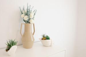 ein weißes Regal mit einer Vase mit Blumen und Pflanzen in der Unterkunft Comeback DONT WORRY BE HAPPY in Salobreña