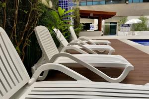 a row of white chairs sitting next to a pool at SHB - The Jewel Pitangueiras with complete leisure in Guarujá