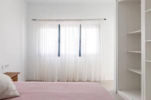 ein Schlafzimmer mit einem Fenster mit weißen Vorhängen in der Unterkunft Sunset Horizon Hideaway & Terrace, Santa Úrsula in Santa Úrsula