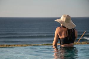 a woman in a hat sitting in the water at Hotel Verde Mar & SPA in Ribeira Grande