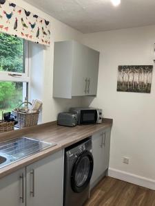 a kitchen with a washing machine and a microwave at Wee Lyon Cottage Maybole 2 Bedroom Sleeps 4 in Maybole