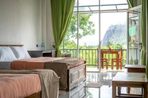 una camera d'albergo con due letti e un balcone di Welcome Homestay a Ella