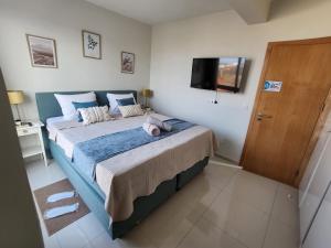 a bedroom with a large bed with a television on the wall at Boa Mindelo Azul in Mindelo