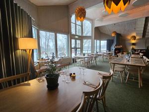 a dining room with tables and chairs and windows at Hotell Lassalyckan in Ulricehamn