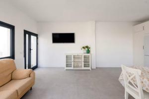 ein Wohnzimmer mit einem Sofa und einem Fernseher an der Wand in der Unterkunft Sunset Horizon Hideaway & Terrace, Santa Úrsula in Santa Úrsula