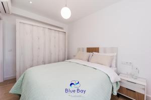 Un dormitorio blanco con una cama con un cartel de caja azul. en La Soleá Historic Center, en La Herradura