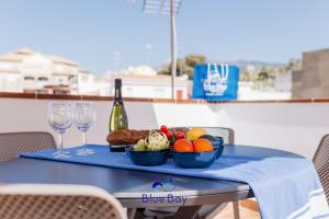 un tavolo blu con un cesto di frutta e una bottiglia di vino di La Soleá Historic Center a La Herradura