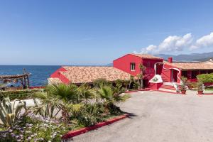 a red house with the ocean in the background at Hôtel Dolce Notte in Saint-Florent