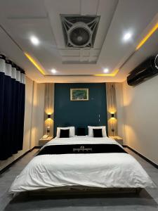 une chambre avec un grand lit avec un mur bleu dans l'établissement Skardu Midway Hotel, à Skardu