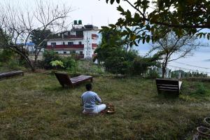 ポカラにあるHIMALAYAN AAMA APARTMENTの建物の前の芝生に座っている男性