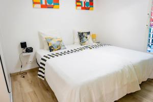 a white bed with pillows on it in a room at Aimeelie - spacieux T3 avec piscine, terrasse, idéal famille, calme et lumineux in Lamentin