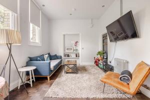 Una sala de estar con un sofá azul y un televisor. en Classroom Flat Suite in a converted school in Fowey town centre, en Fowey