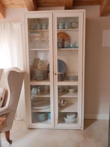 a white cabinet with plates and dishes in it at Lakeview Jonny house on the roofs in Lezzeno