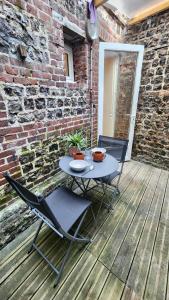 a table and chairs on a wooden deck with a brick wall at Le Moulin in Veules-les-Roses