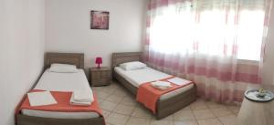 a bedroom with two beds and a table and a window at Roses RT apartments Skioni I in Nea Skioni