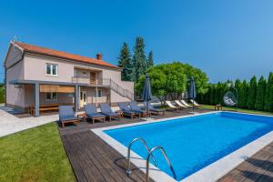 a swimming pool with chairs and a house at Villa Lavanda near Pazin, a modern pool villa in the heart of Istria in Pulići