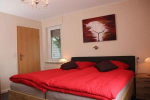 a bedroom with a red bed with a red blanket at Ferienwohnung Voege in Schmallenberg