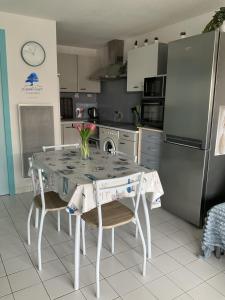 Una cocina con una mesa con sillas y un refrigerador. en Studio Bleu Riviera - Évasion en bord de mer, en Port-la-Nouvelle