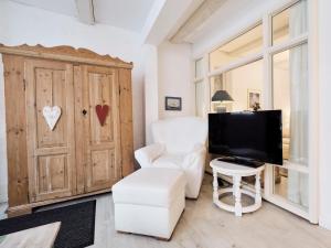 a living room with a white chair and a television at Altstadtapartment- Historischer Charme trifft modernen Komfort zentral & gemütlich mit Parkplatz! in Niederdorla
