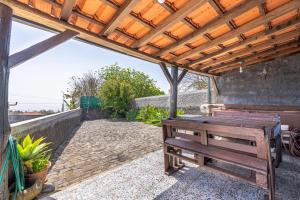 a wooden bench sitting under a wooden pergola at Casa de Campo Serrão in Calheta