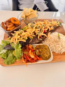 a plate of food with rice and other foods on a table at MERAKI BEACH RESORT Lodges in Lomé