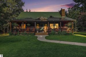 a house with a green roof and a grass yard at Majestic Escapes Hot Tub Firepit Deck Large Yard in Lake Ann