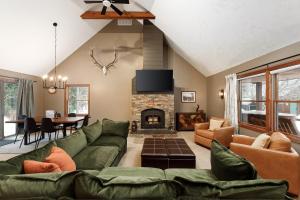a living room with a green couch and a fireplace at Majestic Escapes Hot Tub Firepit Deck Large Yard in Lake Ann