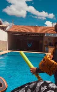 a child holding a baseball bat in a swimming pool at Casa de campo in Caçapava