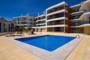 an apartment with a swimming pool in front of a building at Apartamento Varandas do Mar in Olhos de Água