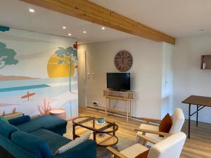 a living room with a blue couch and a tv at Villa émeraude in Cublac