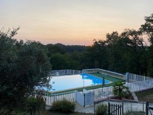 a large swimming pool with a fence and trees at Villa émeraude in Cublac