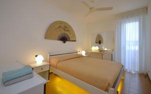 a bedroom with a bed and two tables and a window at Appartamenti La Quercia in Bibione
