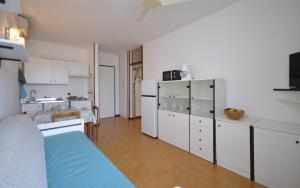 a kitchen with white cabinets and a blue bed in a room at Appartamenti La Quercia in Bibione