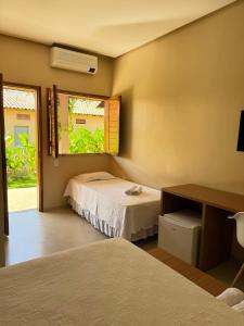 a hotel room with two beds and a window at Hotel do Carmo in Piracuruca