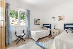 een slaapkamer met een bed, een stoel en een raam bij Villa Tres in Es Mercadal +21 foto's