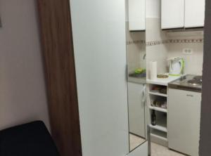 a small kitchen with white cabinets and a refrigerator at Sineva in Šibenik