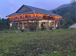 a large wooden house with lights in a field at NaNa Farm in Bak Kan
