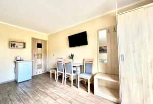 een kamer met een tafel, stoelen en een televisie bij Ośrodek rodzinny "Pod Wydmami" PRZY PLAŻY , PLAC ZABAW , ROWERY in Sarbinowo