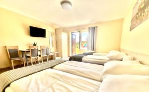 een hotelkamer met 2 bedden en een tafel met stoelen bij Ośrodek rodzinny "Pod Wydmami" PRZY PLAŻY , PLAC ZABAW , ROWERY in Sarbinowo +84 foto's