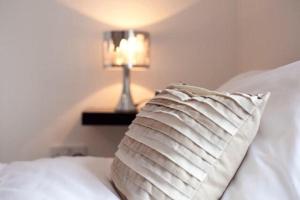 a white pillow sitting on a bed with a lamp at The Loft at Venga in Portishead