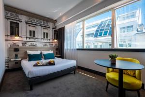 a bedroom with a bed and a table and a window at Nemea Appart Hotel Paris Levallois in Levallois-Perret