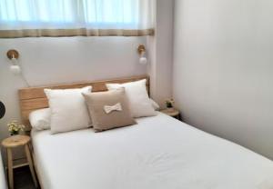 una camera da letto con un letto con lenzuola e cuscini bianchi di Duplex Mediterranea a Benicarló Altre 2 foto