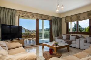 a living room with couches and a flat screen tv at Luxury Villa Amaltheia Rhodes in Koskinou