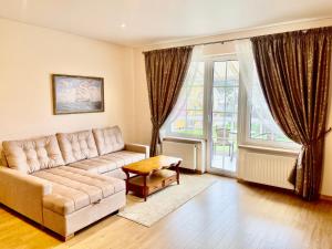 a living room with a couch and a large window at Svečių Apartamentai Vanagupėje in Palanga
