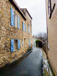 an alley with blue shutters on a stone building at Entre montagne et lavande - Maison Provençale in Saint-Étienne-les-Orgues