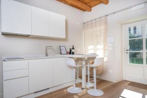 eine weiße Küche mit einer Theke und Stühlen in der Unterkunft Casa vacanze alle Mura in Cividale del Friuli + 42 Fotos